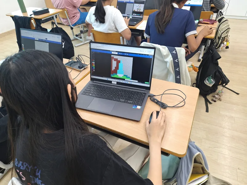 노트북으로 블록 기반 게임을 만드는 학생들의 뒷모습